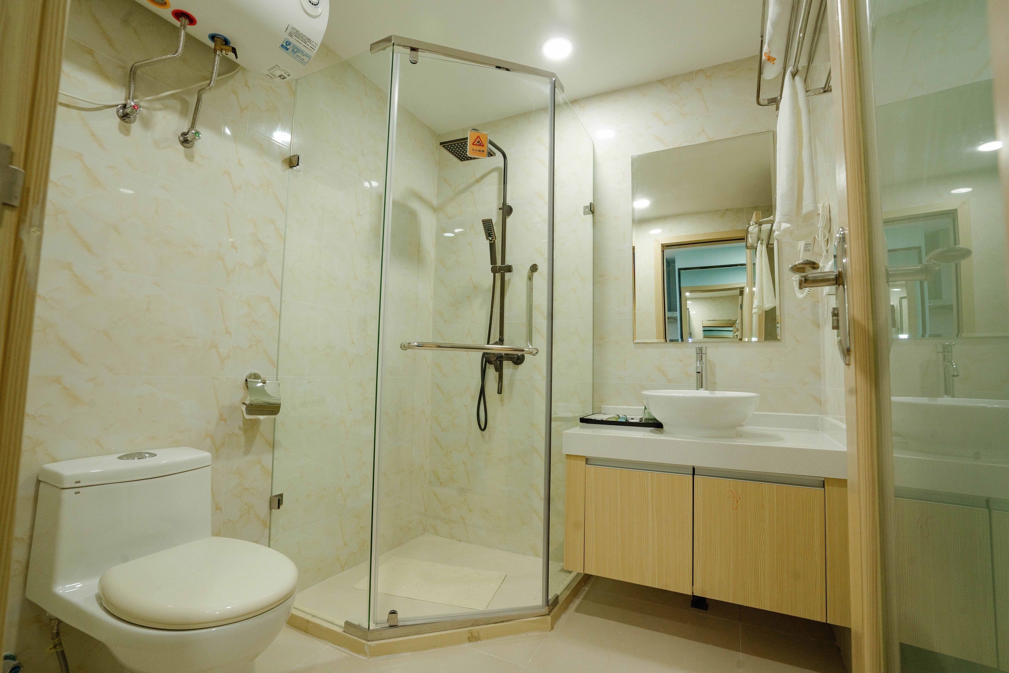 Uma casa de banho moderna com chuveiro de vidro, sanita e lavatório com espelho.