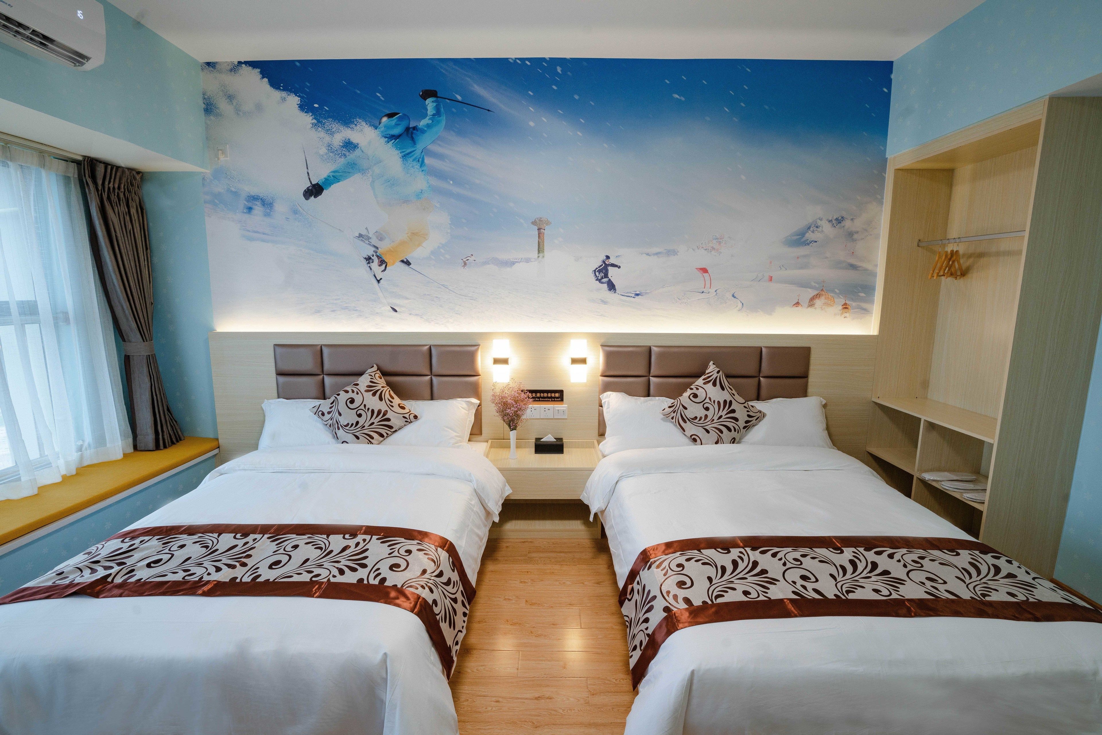A hotel room with two beds, a large mural of a snowy landscape, and a wooden floor.