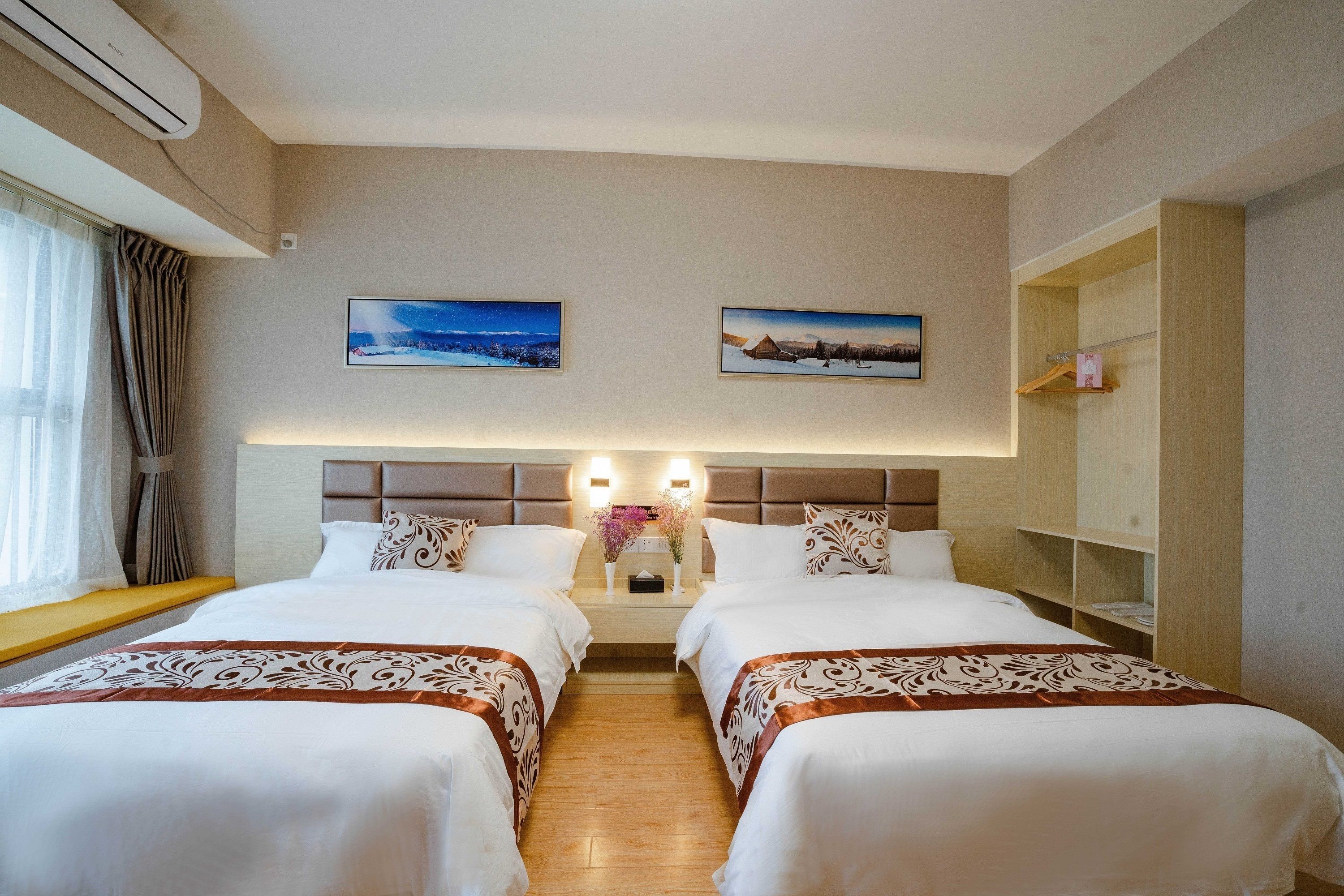 Quarto de hotel com duas camas, cabeceira com iluminação embutida, janela com cortinas e duas imagens penduradas na parede.