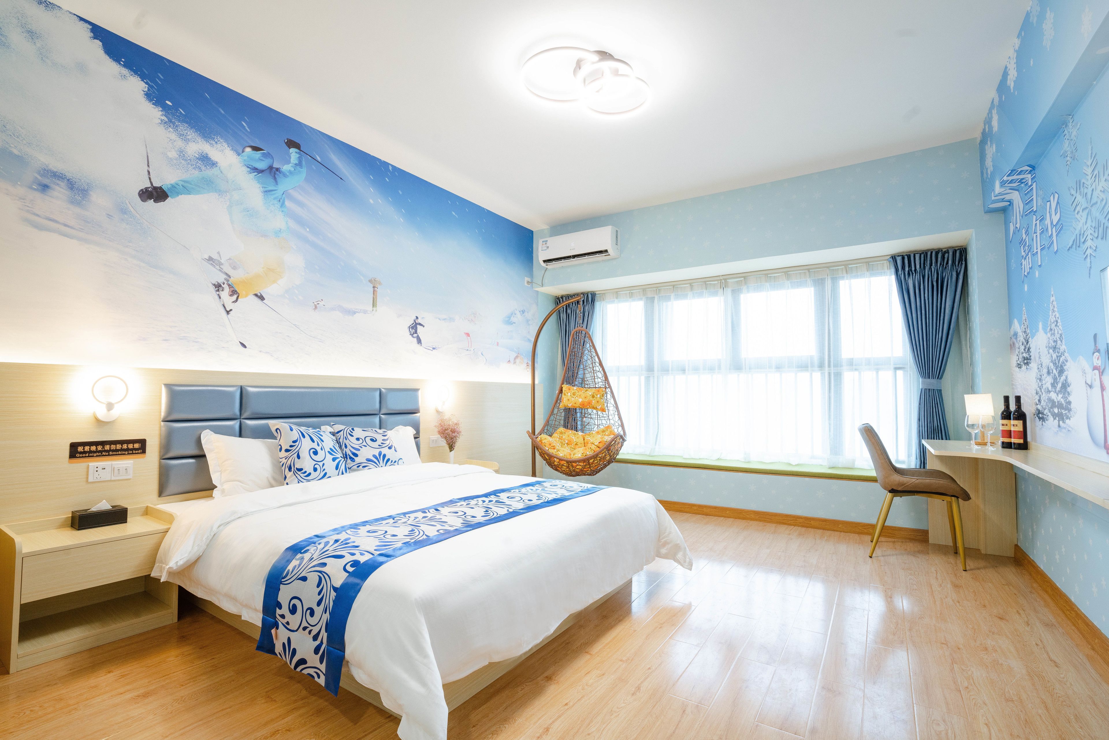 Habitación de hotel con una cama grande, un escritorio con silla, un sillón colgante y una ventana con cortinas.