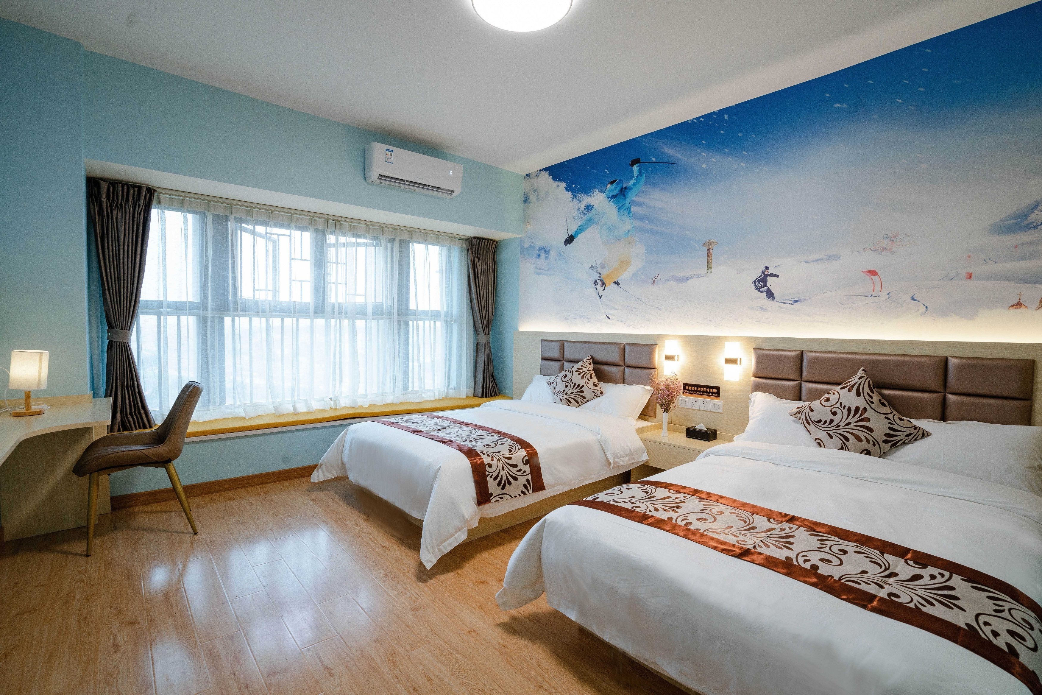 Ein Hotelzimmer mit zwei Betten, einem Schreibtisch, einem Sessel, einem großen Fenster mit Vorhängen und einem Wandgemälde eines Skifahrers.