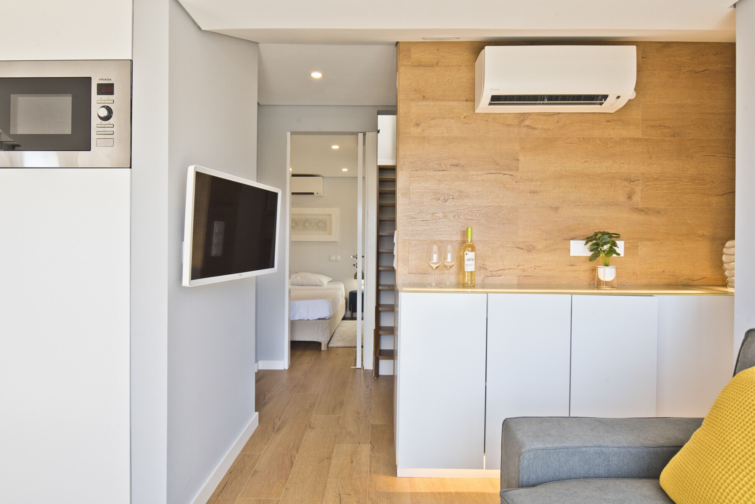 Una cucina moderna con forno a microonde integrato, TV a schermo piatto e parete decorata in legno.