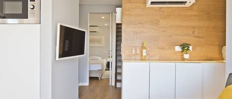 Una cucina moderna con forno a microonde integrato, TV a schermo piatto e parete decorata in legno.
