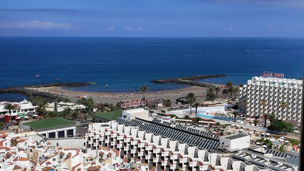A coastal hotel with multiple buildings, a beach, and a rocky breakwater. - Playa de las Américas Apartment (Arona)