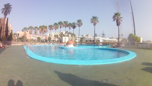 A large outdoor swimming pool with multiple lanes, surrounded by palm trees and lounge chairs. - Playa de las Américas Apartment (Arona)