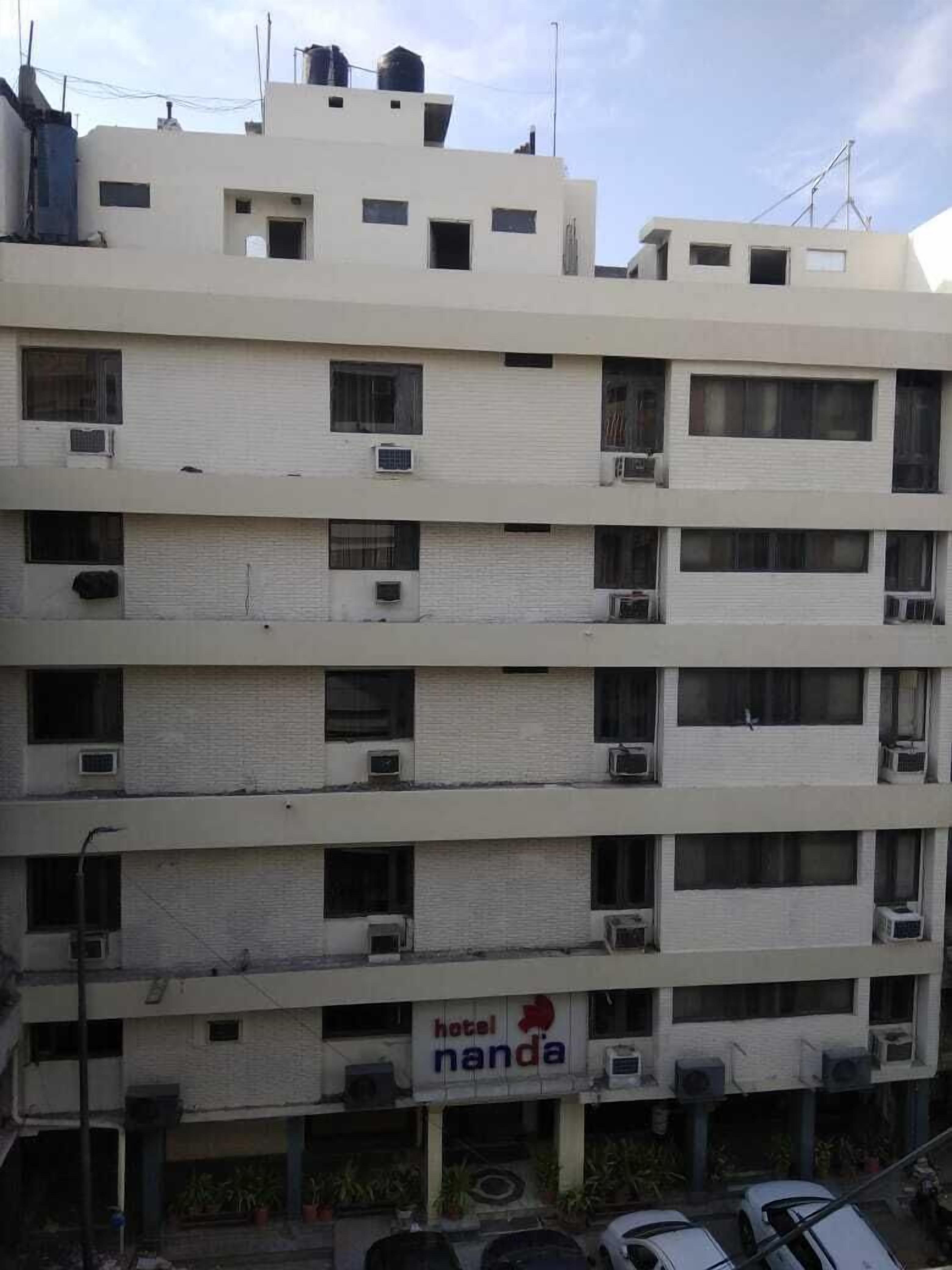 A multi-story hotel building with balconies and air conditioning units.
