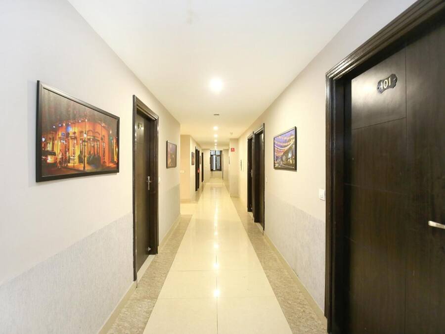 Un pasillo de hotel con puertas numeradas 101 y 102, piso de baldosas y cuadros enmarcados en las paredes.