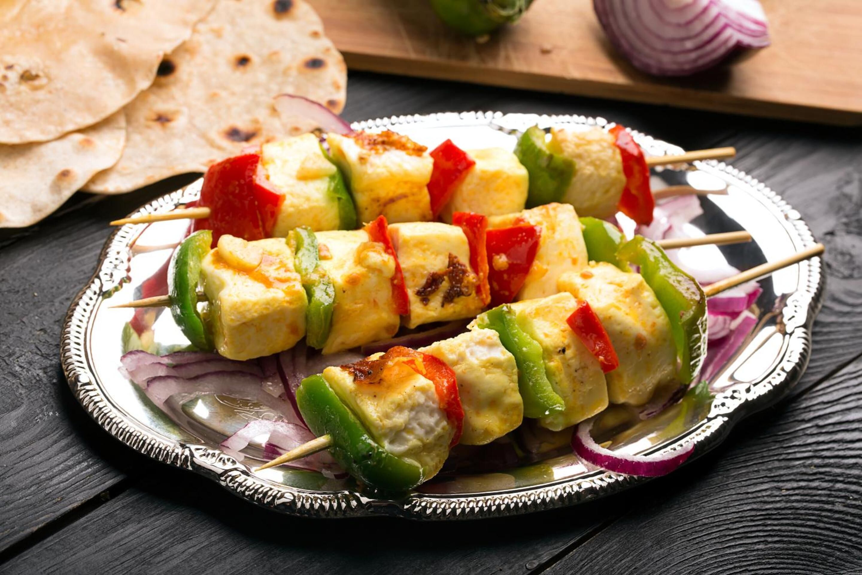 Ein Teller mit Gemüsespießen und Paneer auf einer verzierten Platte.