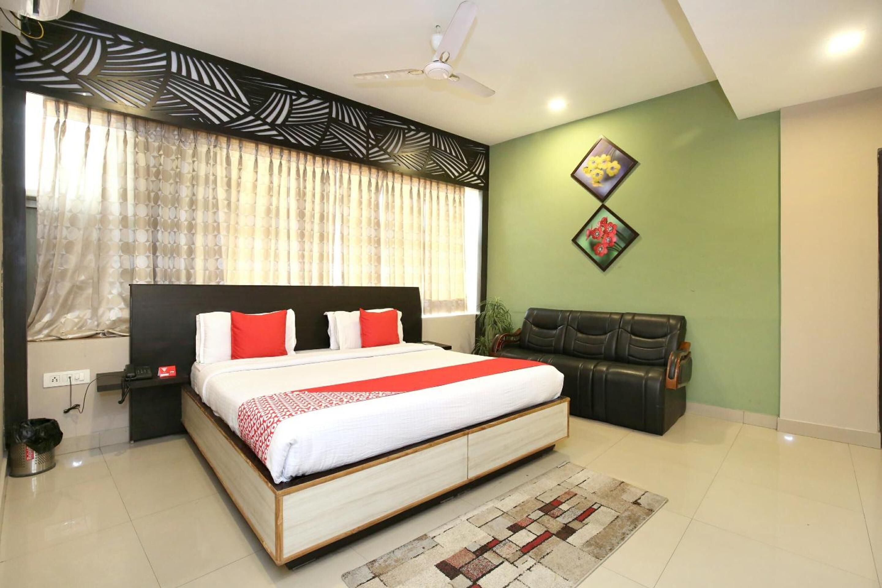 A bedroom with a large bed, a ceiling fan, a sofa, and a decorative wall piece.