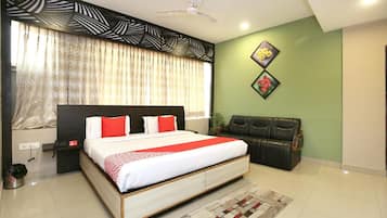 A bedroom with a large bed, a ceiling fan, a sofa, and a decorative wall piece.