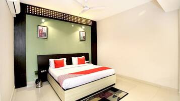 A bedroom with a bed, a ceiling fan, a wall-mounted air conditioner, and two framed pictures.