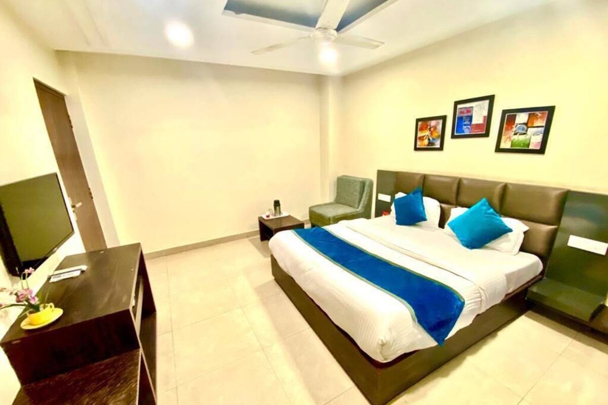 A hotel room with a bed, a desk, a chair, and a TV.