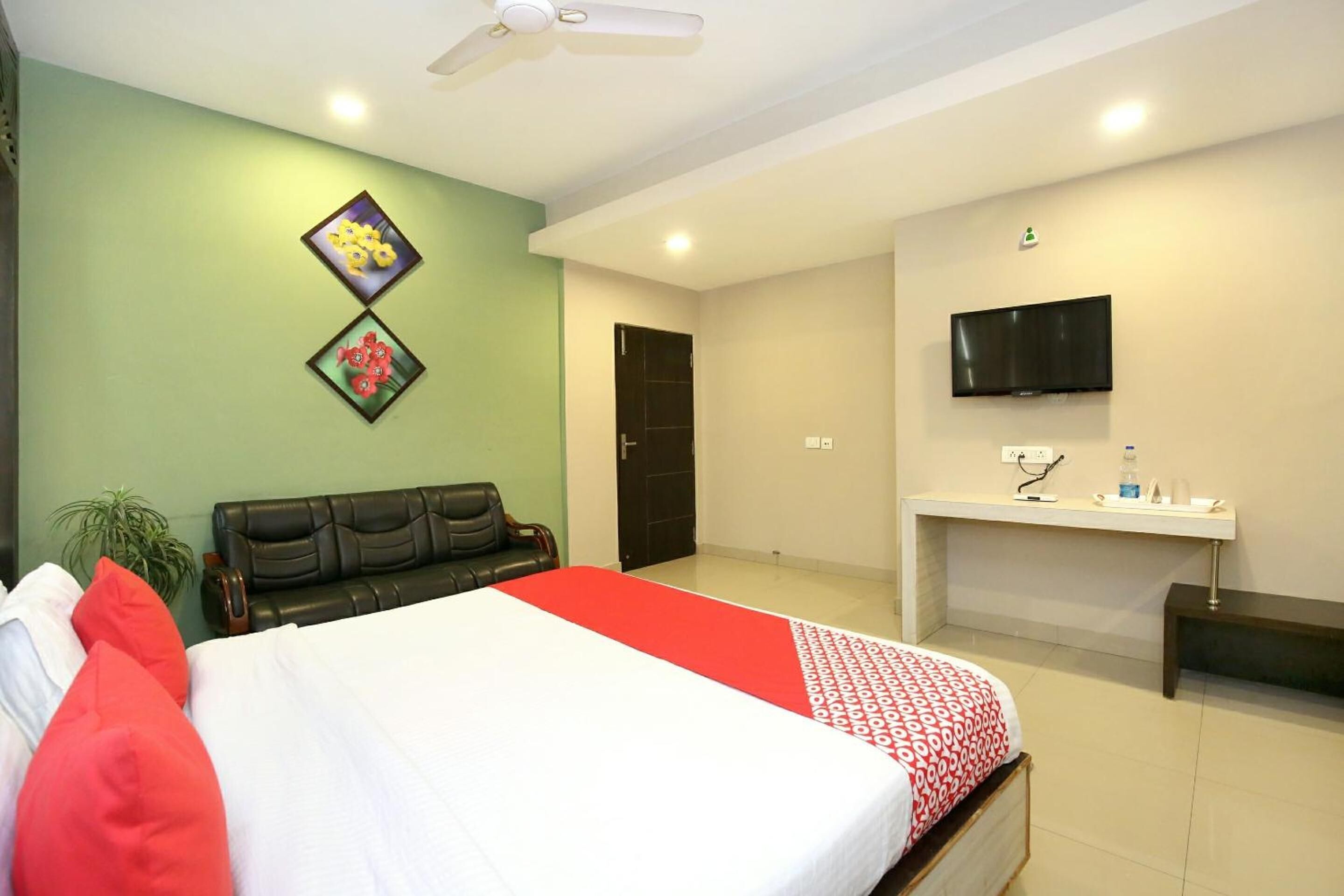 Una habitación de hotel con una cama, un escritorio, un televisor y una puerta.