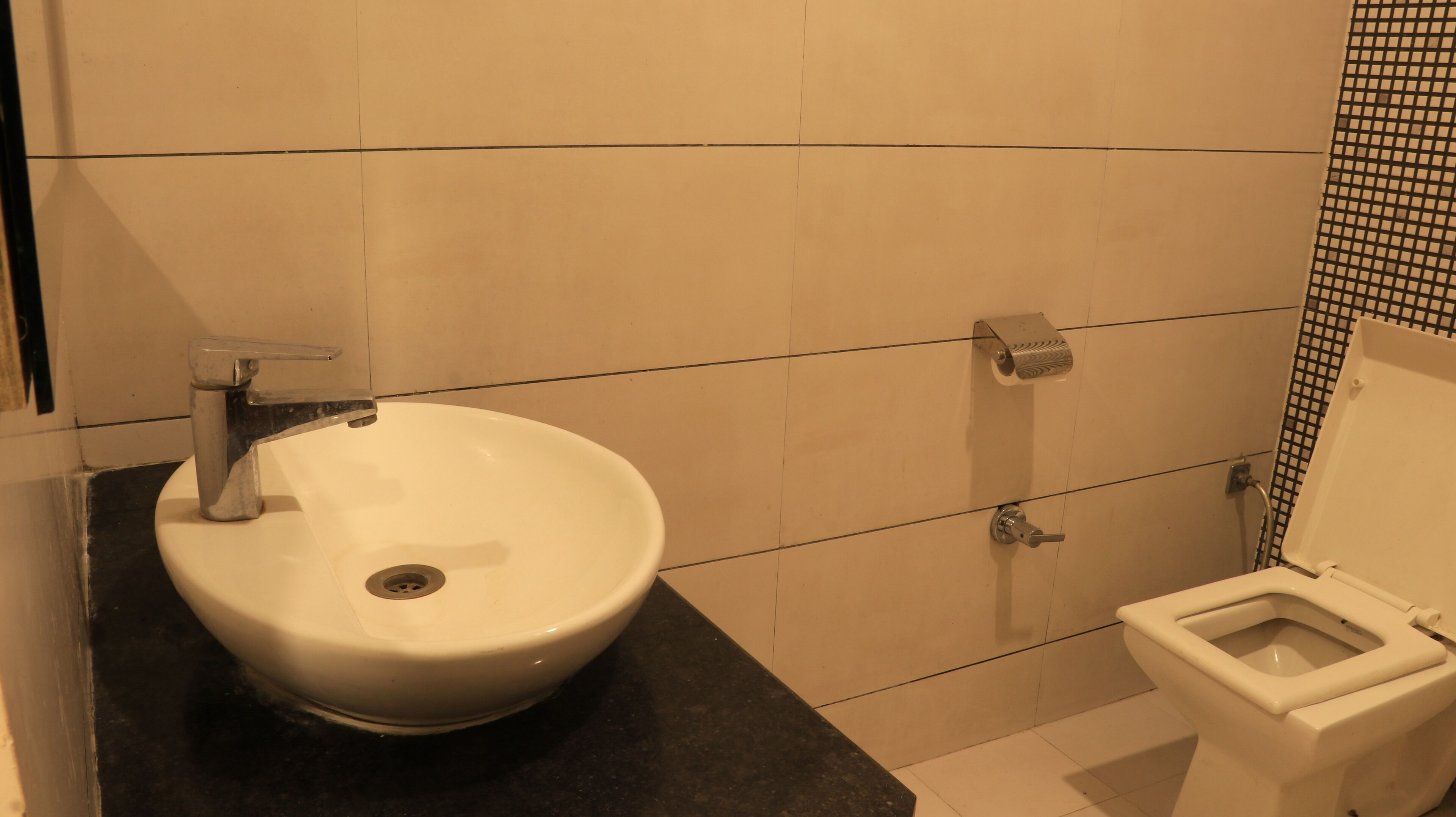 Un baño con un lavamanos blanco, inodoro y paredes con azulejos.