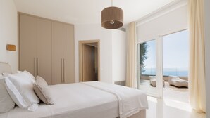 Un dormitorio con cama, armario y vista al mar.