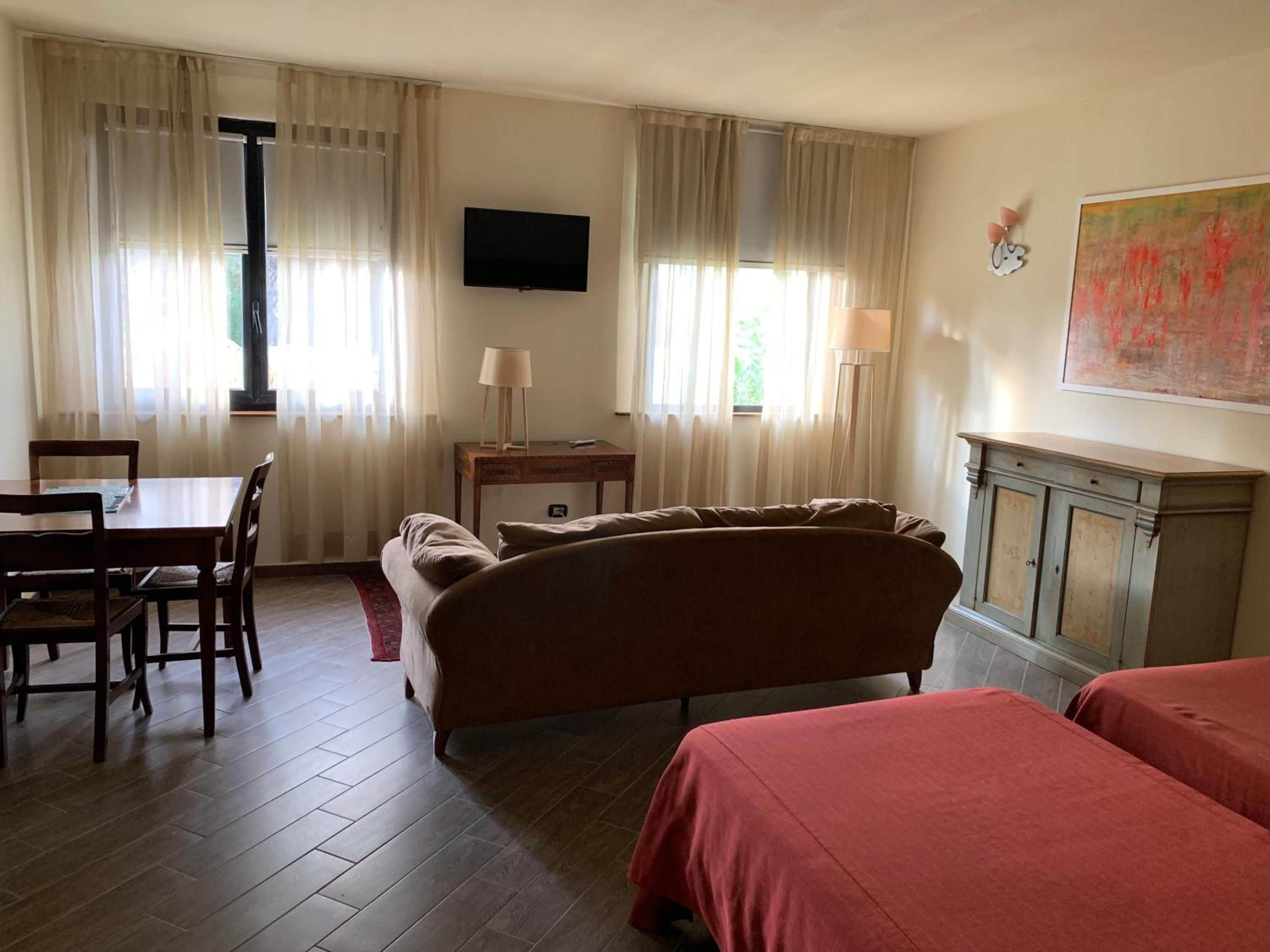 Ein Hotelzimmer mit Bett, Schreibtisch, Stuhl, Fernseher und einem Bild an der Wand.