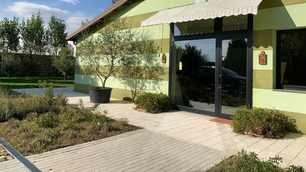 Een gebouw met een bord waarop 'Il Casale Verde' staat en een grote potplant ervoor.