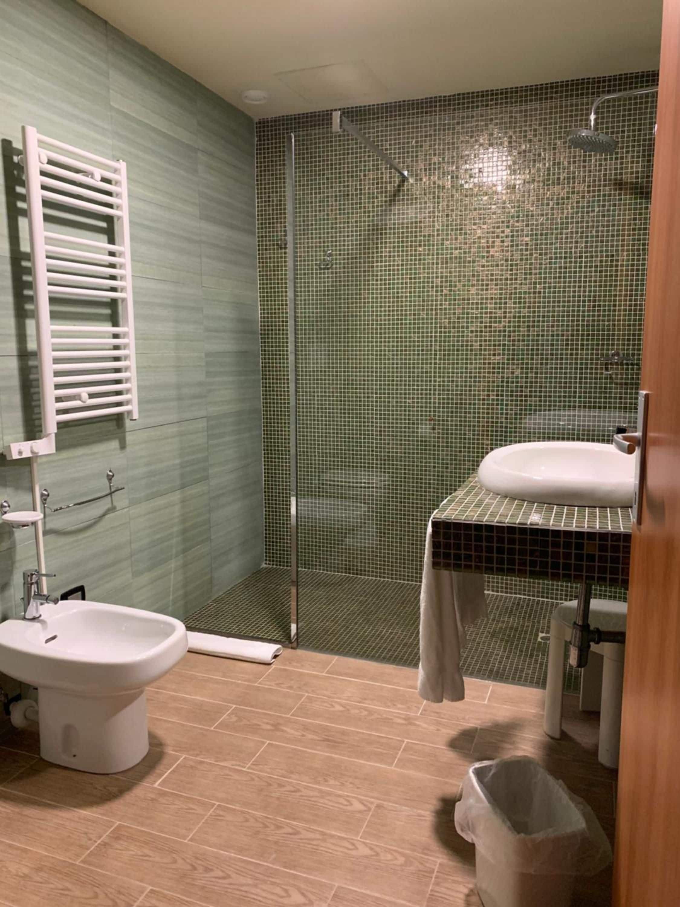 A bathroom with a shower, a sink, a toilet, and a bidet.