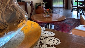 Een woonkamer met een ronde houten salontafel, een glazen vaas met oranje bladeren, een televisie, en een eethoek met een tafel en stoelen.
