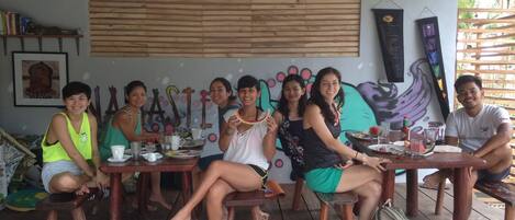 Un grupo de personas sentadas en una mesa de madera, con un mural de fondo.