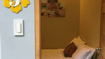 Un dormitorio pequeño y acogedor con una cama, una mesita de noche y una lámpara fijada a la pared.