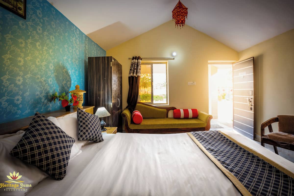 A bedroom with a bed, a sofa, a window, and a door.
