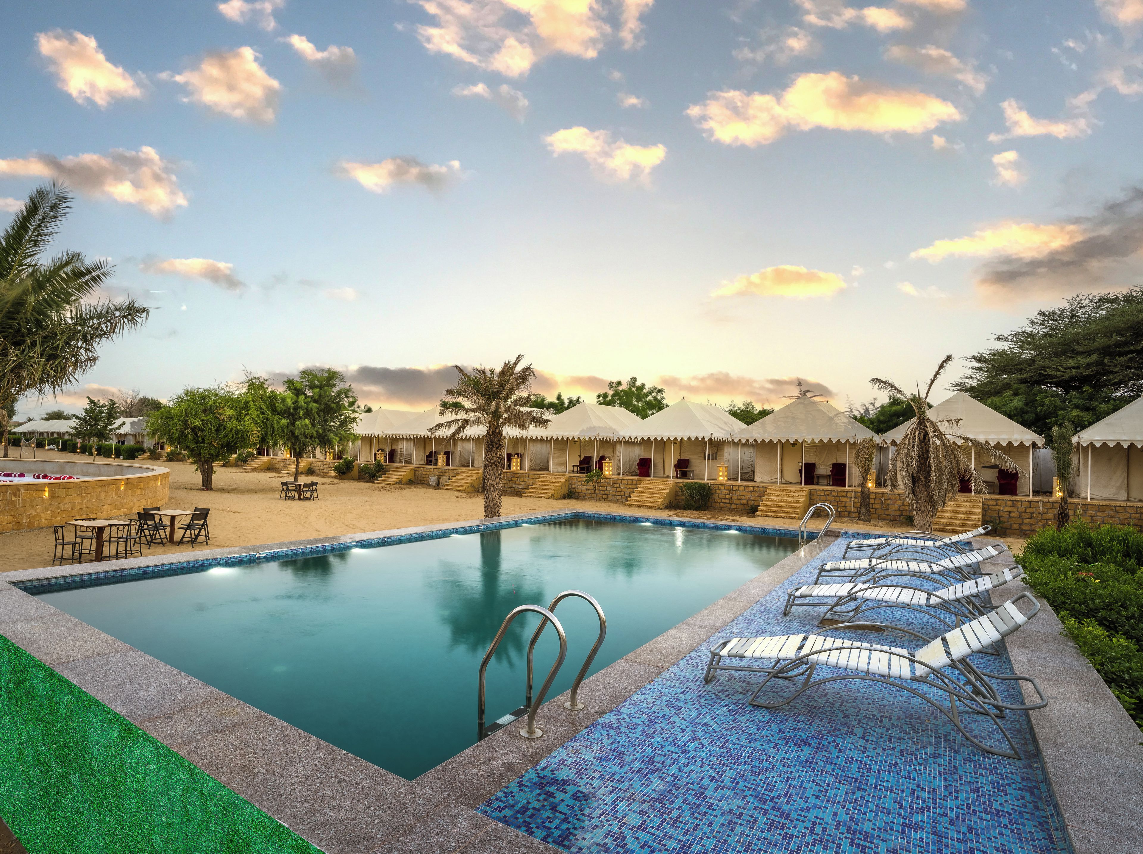 A resort pool with lounge chairs, palm trees, and a clear sky.