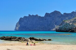 Ein Strand mit Felsformationen und klarem, blauem Wasser.
