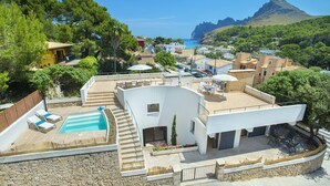 Eine moderne Villa mit Swimmingpool, Sitzgelegenheiten im Freien und Blick auf das Meer und die Berge.