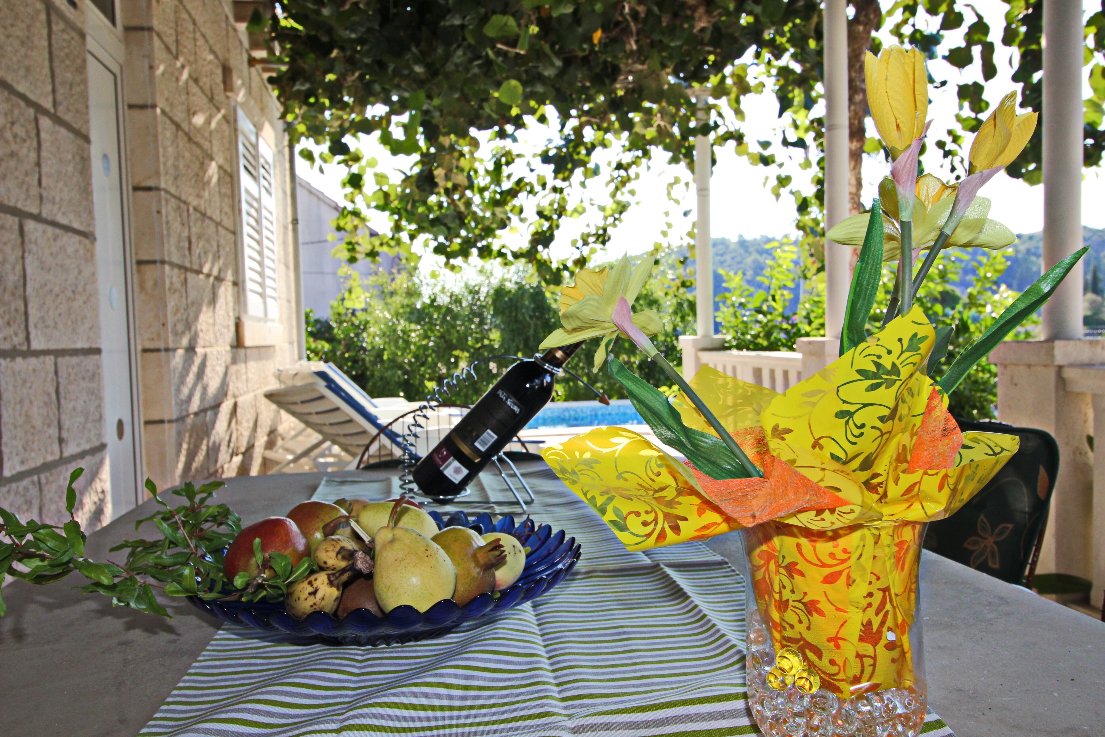 A table with a wine bottle, a bowl of fruit, and a decorative vase.