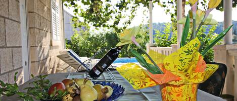 A table with a wine bottle, a bowl of fruit, and a decorative vase.