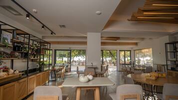 A modern cafe with wooden furniture, large windows, and a view of the outdoors.