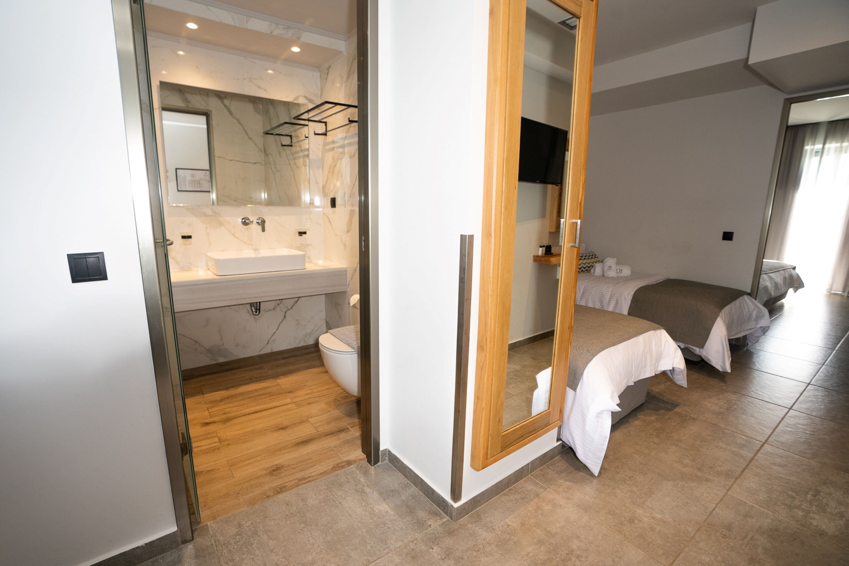 Ett modernt hotellrum med badrum som har en handfat i marmor och ett trägolv.