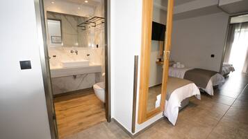 Ett modernt hotellrum med badrum som har en handfat i marmor och ett trägolv.
