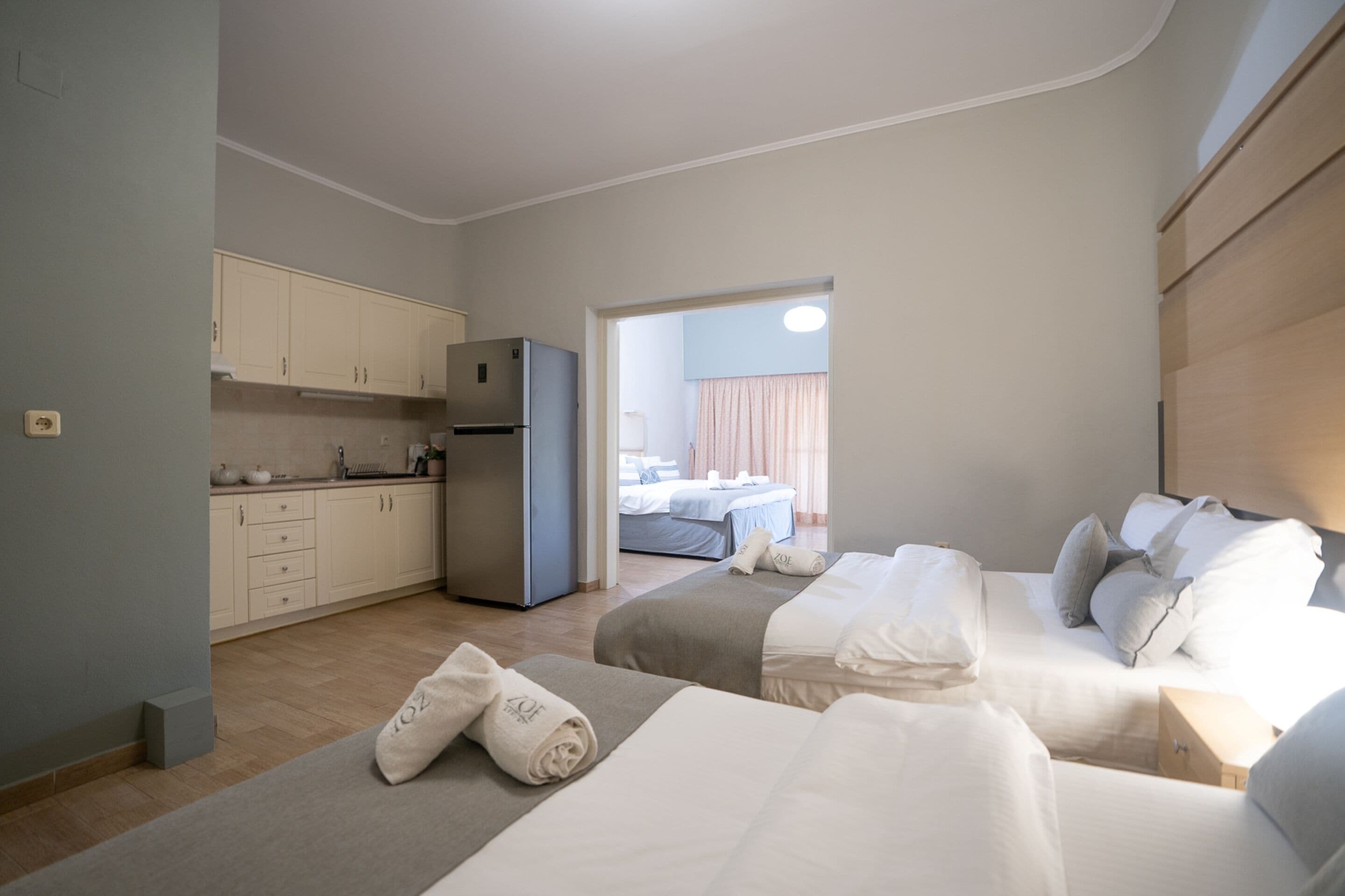 Ein kleines Hotelzimmer mit Küchenzeile, zwei Betten und Blick in den Schlafbereich.