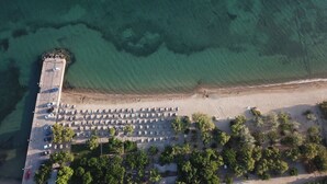 Vue aérienne d’une plage avec un espace de stationnement, des parasols et des arbres.