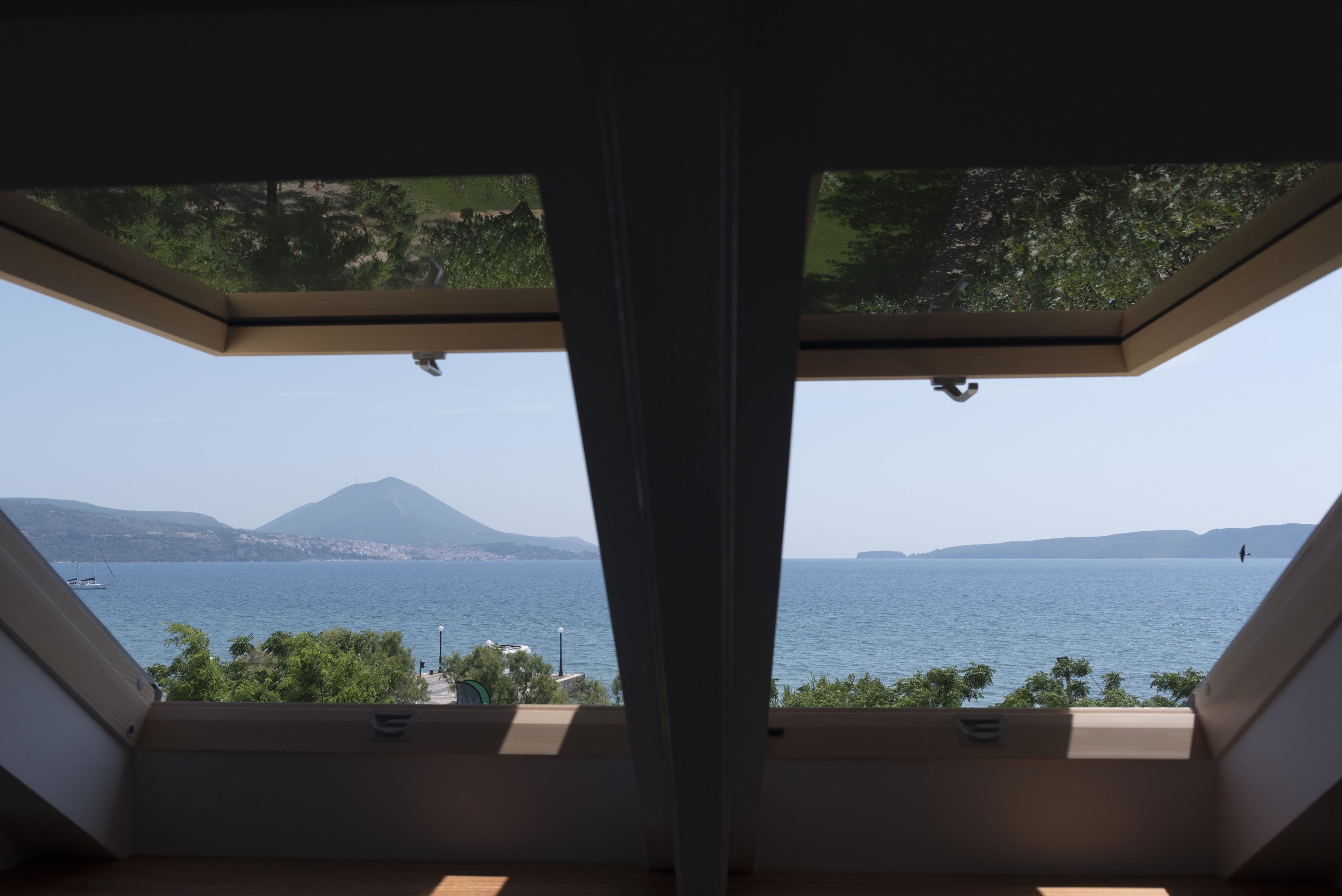 A room with a view of a body of water and mountains.