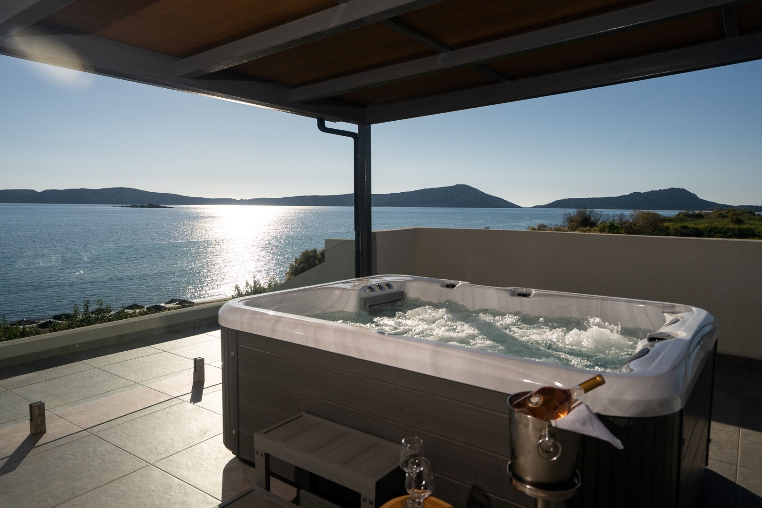 A hot tub on a balcony with a view of the sea and hills.