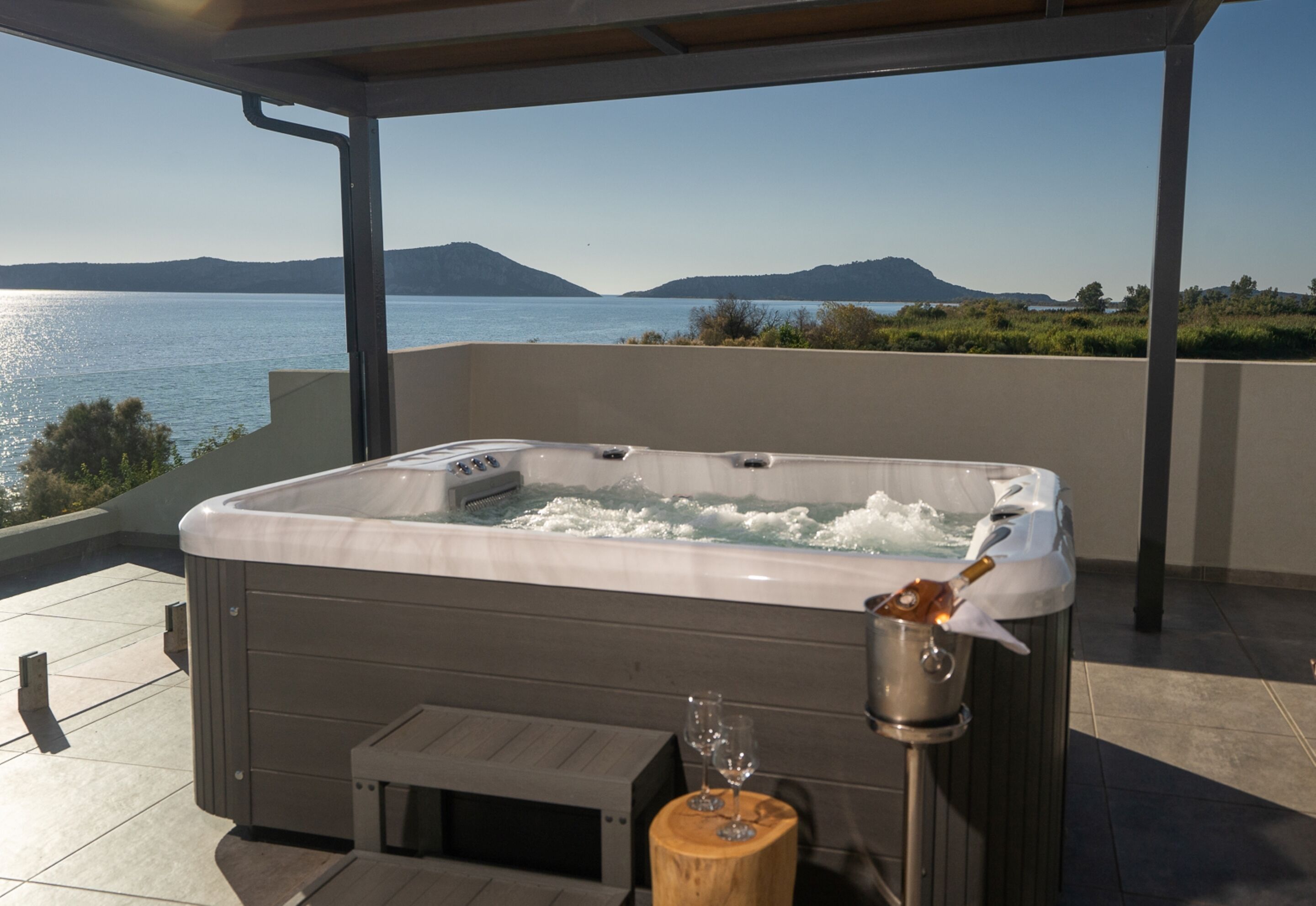 Un bain à remous sur une terrasse offrant une vue sur un lac et des montagnes.
