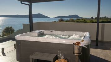 Un bain à remous sur une terrasse offrant une vue sur un lac et des montagnes.