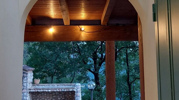 Un espace extérieur aménagé en terrasse, avec une cheminée en pierre, des chaises blanches et une pergola en bois.