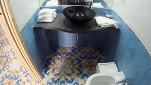 A bathroom with a black sink, white basin, blue and orange patterned floor tiles, and a white toilet. - Casa Niccolo apartment complex (Napoli)