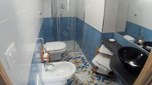 A bathroom with a shower, toilet, bidet, sink, and a large mirror. - Casa Niccolo apartment complex (Napoli)