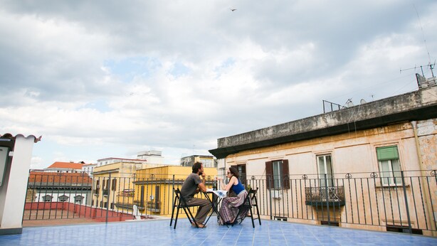 A rooftop terrace with a blue tiled floor, a metal railing, and a view of surrounding buildings. - Casa Niccolo apartment complex (Napoli)