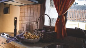 Una cocina con un lavamanos, un cuenco de limones, una cesta y una ventana con cortinas.