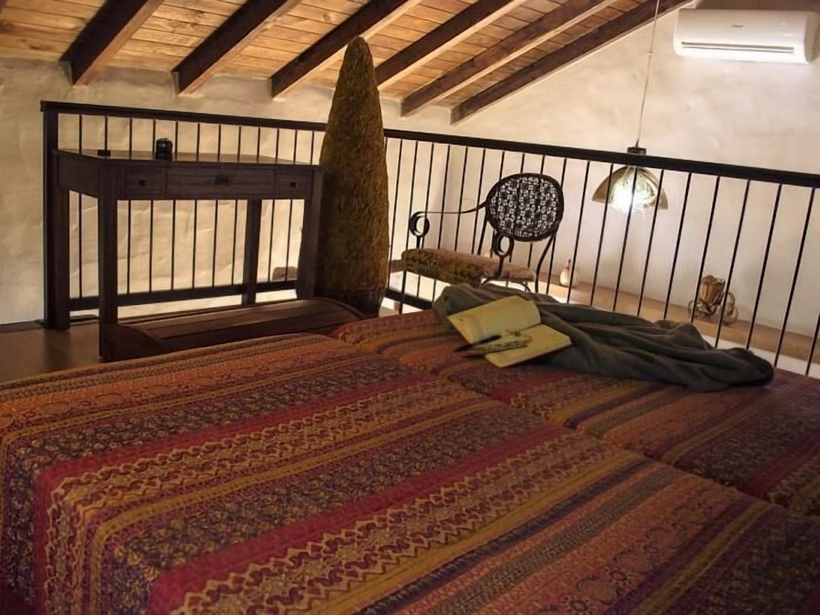 A bedroom with a large bed, a wooden headboard, a small table, and a chair.