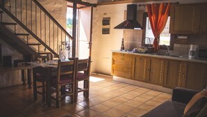 Una sala de estar acogedora con una escalera de madera, un comedor y una cocina con armarios de madera y salpicadero de azulejos.