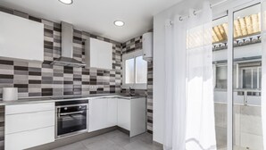 A modern kitchen with white cabinets, a built-in oven, and a tiled backsplash. - Rental unit in Port de Sagunt · ★4.60 · 3 bedrooms · 3 beds · 2 baths (Port de Sagunt)