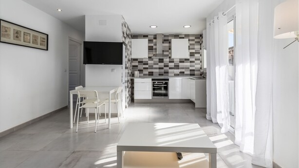 A modern kitchen with white cabinets, a black and white checkered backsplash, and recessed ceiling lights. - Rental unit in Port de Sagunt · ★4.60 · 3 bedrooms · 3 beds · 2 baths (Port de Sagunt)