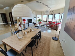 Un amplio salón con una gran mesa de comedor, un conjunto de sofás y vistas al paisaje desértico a través de amplias ventanas.